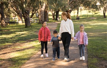 A woman and three kids walking on a path